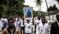 A Supporter of Democratic Republic of Congo new President shows a portrait of outgoing President Joseph Kabila, ahead of the Presidential Inauguration on January 24, 2018.  AFP / John WESSELS
