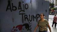 A woman walks past a grafitti depicting late Venezuelan president Hugo Chavez (R), President Nicolas Maduro and a legend reading 