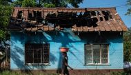 A young woman carries a bowl on her head as she walks past the shell of the burnt-out offices belonging to the ruling ZANU PF party's Kadoma district in Rimuka township, Kadoma on January 24, 2019. / AFP / ZINYANGE AUNTONY 