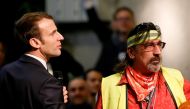 French President Emmanuel Macron stands near a man who wears a yellow vest as he attends a meeting with local residents as part of the 