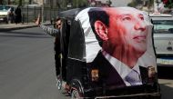 A man gestures as he rides a motorized vehicle showing a poster of Egyptian President Abdel Fattah al-Sisi in Cairo, March 27, 2018. Reuters/Ammar Awad