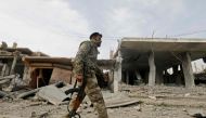 A fighter from the Syrian Democratic Forces (SDF) walks past a former Islamic State (IS) group jihadist alms tax centre in the city of Hajin in Syria's eastern Deir Ezzor province on January 27, 2019 after the Kurdish-led and US-backed SDF retook the city