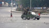 Indian Army soldiers in a vehicle patrol a street as a woman walks past during a curfew in Jammu, February 17, 2019. REUTERS/Mukesh Gupta