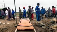 Men walk past a stretcher during an ongoing rescue and recovery operation at the flooded Cricket gold mine near Kadoma, Zimbabwe, on February 17, 2019.   AFP / Jekesai NJIKIZANA