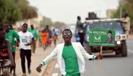 A supporter runs holding an election poster of the Party of Unity and Assembly (PUR) candidate Issa Sall during his campaign in Dahra Djoloff, Louga region, Senegal February 18, 2019.  Reuters/Sylvain Cherkaoui

 