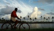 A man rides a bicycle against the backdrop of monsoon clouds on the outskirts of Kochi in this Reuters file photo. Kerala, which suffered its worst floods in a century last year, is bracing itself for more extreme weather conditions in 2019 and the state'
