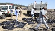 Rescue team walk past collected bodies in bags at the crash site of Ethiopia Airlines near Bishoftu, a town some 60 kilometres southeast of Addis Ababa, Ethiopia, on March 10, 2019.  AFP / Michael Tewelde 