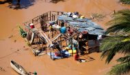 A local paddles past a woman at her home during floods after Cyclone Idai, in Buzi district, outside Beira, Mozambique, March 21, 2019. REUTERS/Siphiwe Sibeko