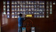In this photo taken on April 20, 2019, a worker dusts memorial portraits of party workers killed in political violence hanging at the Rashtriya Swayamsevak Sangh (RSS) office at Thalaserry in the southern Indian state of Kerala. BHUVAN BAGGA / AFP / ARUN 
