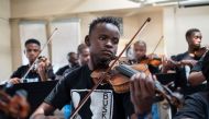 Xolani Zingeni (C), 16, plays with young students and orchestra members from Buskaid during a practice of the South African national Anthem, ahead of a performance for a grant application, at the Reformed Presbyterian Church in Diepkloof, Soweto, on April