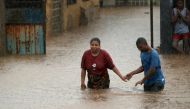 A man helps a woman through a flooded neigbourhood in the aftermath of Cyclone Kenneth in Pemba, Mozambique, April 28, 2019. REUTERS/Mike Hutchings