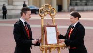 Members of staff set up an official notice on an easel at the gates of Buckingham Palace in London on May 6, 2019 announcing the birth of a son to Britain's Prince Harry, Duke of Sussex and Meghan, Duchess of Sussex. (AFP / Tolga AKMEN)