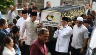 Former Indonesian President Susilo Bambang Yudhoyono (left in white) walks next to a casket carrying his wife Ani Yudhoyono, who passed away in Singapore on June 1, 2019. / AFP / ROSLAN RAHMAN