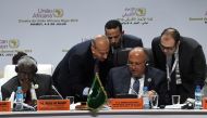 Egyptian Foreign Minister Sameh Shoukry (C) reads a document next to Chairperson of the African Union Commission Moussa Faki Mahamat (L) on the second day of the 35th Ordinary Session of the Executive Committee of the Meeting of the African Union at the P
