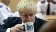 Britain's Prime Minister Boris Johnson drinks from a HMP Leeds prison mug as he talks with prison staff during a visit to HM Prison Leeds, a Category B men's prison in Leeds, northern England, on August 13, 2019. / AFP / POOL / Jon Super