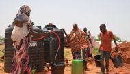 Displaced residents of Niamey collect water at tanks on September 11, 2019 in the makeshift camp of Saguia near the capital after the Niger river floods forced inhabitants out of the area. AFP / Boureima Hama  