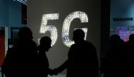 Visitors shake hands next to a 5G hotspot sign at the Mobile World Congress in Barcelona on February 27, 2019. AFP / Pau Barrena