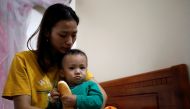 Hoang Thi Thuong, wife of Nguyen Dinh Tu, a Vietnamese suspected victim in a truck container in UK, holds her son Nguyen Dinh Dan at their home in Nghe An province, Vietnam October 26, 2019. REUTERS/Kham