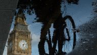 Big Ben is reflected in a puddle as a cyclist rides by in London on  June 27, 2016. AFP/ Leon Neal 