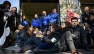 Activists seat in front of police officers to blocking an entrance at Geneva airport's private jet terminal, during a protest by the climate change action group Extinction Rebellion (XR), on November 16, 2019. / AFP / Fabrice Coffrini 