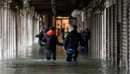 People wade through water under arcades at St. Mark's Square during high tide in Venice, Italy November 17, 2019. REUTERS/Alberto Lingria
