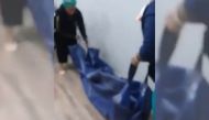 In a video clip that has gone viral on social media, two women can be seen schlepping a blue plastic body bag into an insurance office as stunned clients look on.