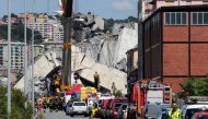 Firefighters and rescue workers stand at the site of a collapsed Morandi Bridge in the port city of Genoa, Italy August 15, 2018. Reuters/Stefano Rellandini