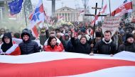 People carry a giant historical Belarusian white-red-white and anti-integration banners as they attend an opposition rally against a Belarusian-Russian integration project in Minsk, on December 7, 2019.   AFP / Sergei GAPON
