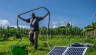 A Kenyan farmer carries the hose of his solar water pump in Kisumu county, Kenya on June 2018. Photo Courtesy: Futurepump/Dan Odero