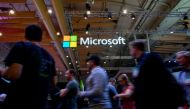 In this file photo taken on November 6, 2019 Attendees walk past the logo of US multinational technology company Microsoft during the Web Summit in Lisbon. / AFP / AFP / PATRICIA DE MELO MOREIRA