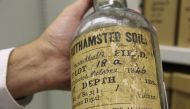 A scientist at Rothamsted Research holds a glass bottle with soil sample dating back to October 1846 in Harpenden in southeast England, September 12, 2019. Thomson Reuters Foundation / Thin Lei Win