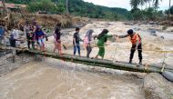 Police officers help people to get through an emergency bridge over the Cidurian river in Bogor, Indonesia, January 3, 2020 in this photo taken by Antara Foto. Antara Foto/Arif Firmansyah/ via REUTERS