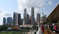 Singapore's city skyline is seen as visitors take photographs from the rooftop bar of the National Gallery on January 13, 2020. / AFP / Roslan RAHMAN
