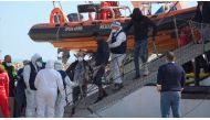 Medical officials wearing protective suits due to the coronavirus outbreak, assist a migrant disembarking from Open Arms rescue ship in Pozzallo, Italy, February 2 2020. Local Team/Reuters TV