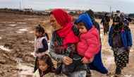 Syrian women accompany children in a muddy field in the Washukanni Camp for the internally displaced, near the predominantly Kurdish city of Hasakeh in northeastern Syria, on February 17, 2020. AFP / Delil Souleiman 