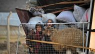 Displaced Syrians ride in the back of a truck as they arrive to Deir al-Ballut camp in Afrin's countryside along the border with Turkey, on February 19, 2020. (AFP / Rami al SAYED)