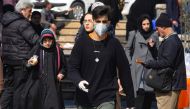 A young Iranian man wearing a protective mask, walks in a busy street in the capital Tehran on February 22, 2020.  AFP / ATTA KENARE