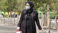 A woman wears a protective mask while walking along the side of a street in the Iranian capital Tehran on February 24, 2020. AFP / ATTA KENARE
