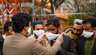 A volunteers (L) hands out free facemasks to people as a preventive measure against the spread of the COVID-19 coronavirus, in Herat city on February 26, 2020.  AFP / HOSHANG HASHIMI