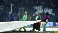 Ground staff members cover the pitch during rain showers during the Pakistan Super League (PSL) T20 cricket match between Karachi Kings and Multan Sultans at the Gaddafi Cricket Stadium in Lahore on March 6, 2020. AFP / Arif Ali

