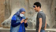 A tourist wearing a protective face mask checks her phone while on a visit to Luxor Temple in Egypt's southern city of Luxor on March 9, 2020. AFP