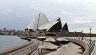 A seating area (below) normally filled with tourists remains empty along Circular Quay in Sydney on March 25, 2020, as people stay away due to restrictions to stop the spread of the worldwide COVID-19 coronavirus outbreak. / AFP / Saeed KHAN