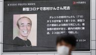A man wearing a protective face mask, following an outbreak of the coronavirus disease (COVID-19), walks past in front of a huge screen reporting death of Japanese comedian Ken Shimura, who had been hospitalised after being infected with the new coronavir
