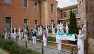 :Careworkers from the Juan Calzada nursing home stand behind a banner reading 
