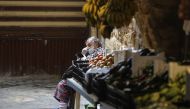 A Lebanese man sitting by a fresh produce stall checks his phone in the market of the historic part of the southern coastal city of Saida, on April 6, 2020. AFP / JOSEPH EID