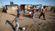 :A township child plays soccer as residents wait to receive food packages handed out by a non governmental organisation during a 21-day nationwide lockdown aimed at limiting the spread of coronavirus disease (COVID-19) in Cape Town, South Africa, April 17