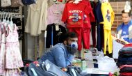 An Iranian shopkeeper wearing protective gear amid the COVID-19 pandemic watches the street from a clothes stall at the Grand Bazaar market in the capital Tehran, on April 18, 2020. AFP / ATTA KENARE
