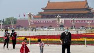 People wearing face masks following the coronavirus disease (COVID-19) outbreak walk past flower installations set up to mark the upcoming Labour Day holiday, at Tiananmen Square in Beijing, China April 29, 2020. 