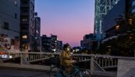 A woman wearing a face mask rides a bicycle in Tokyo on April 29, 2020. / AFP / Philip FONG