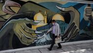 A man wearing a protective face mask walks past a Palestine mural on the wall following the outbreak of the coronavirus disease (COVID-19), in Tehran, Iran, April 30, 2020. 